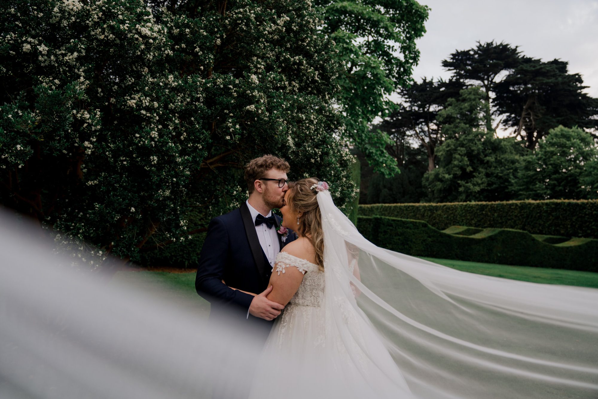 bride and groom in an embrace with long veil blowing in the wind