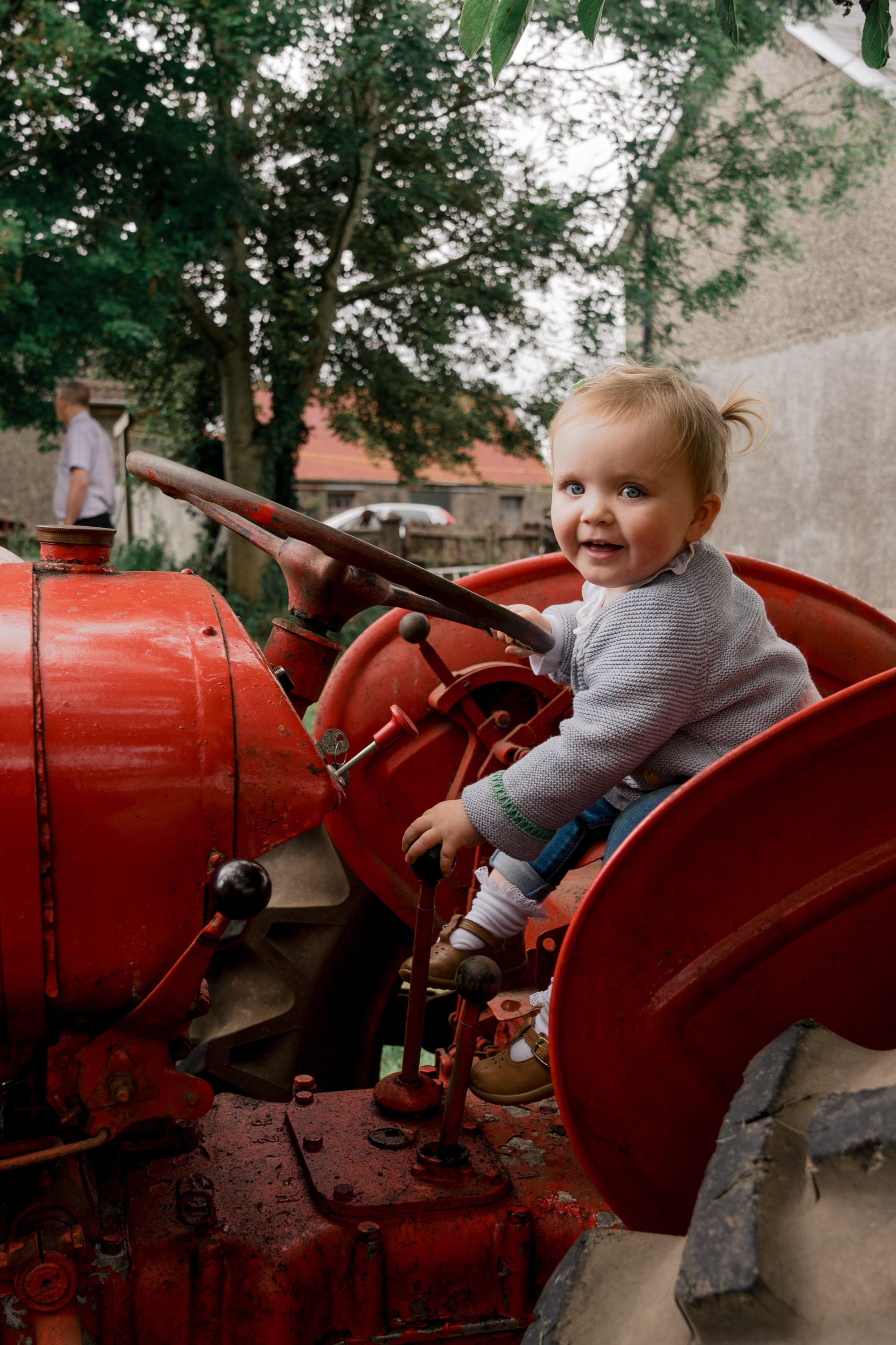 Young child sitting on a vintage tractor during an outdoor family photography session near Randalstown.