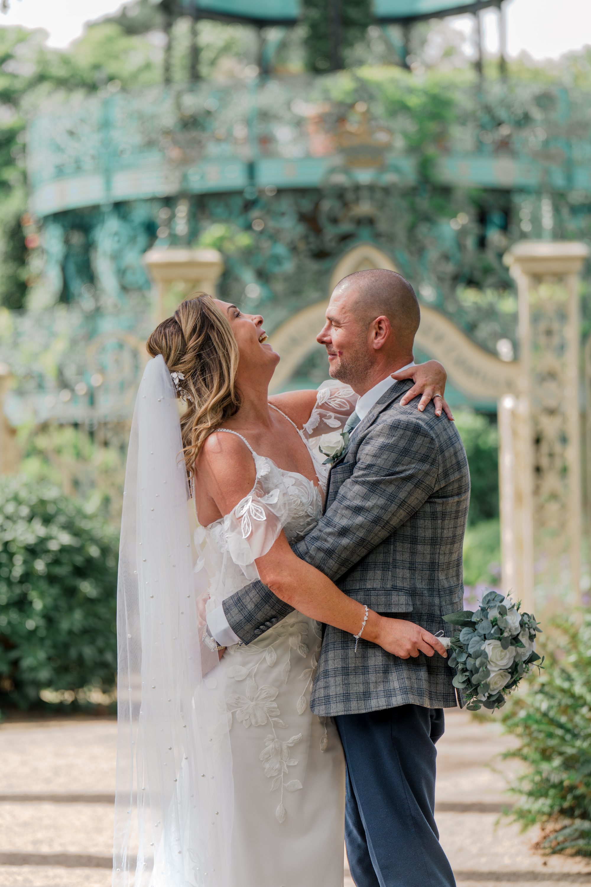 Bride and groom embracing during relaxed outdoor wedding portraits.